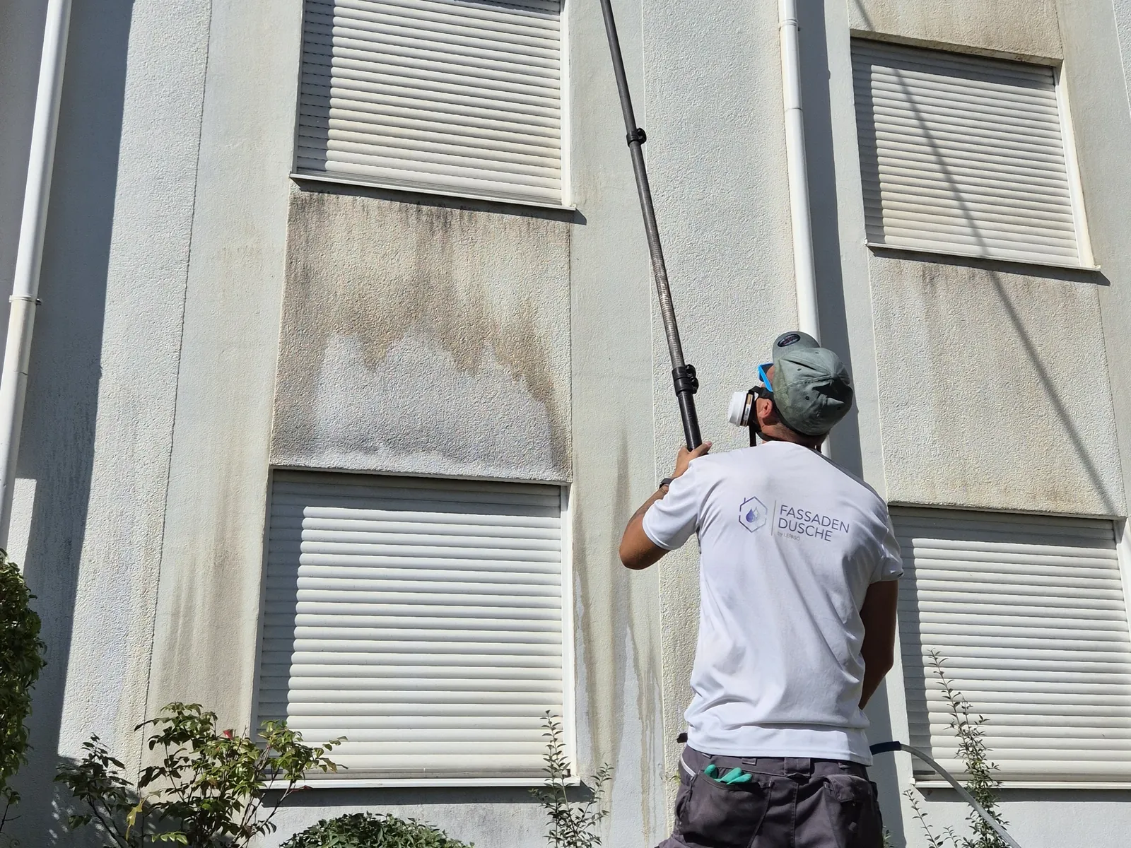 Mitarbeiter reinigt die verschmutzte Fassade mit der Teleskoplanze im Niederdruck
