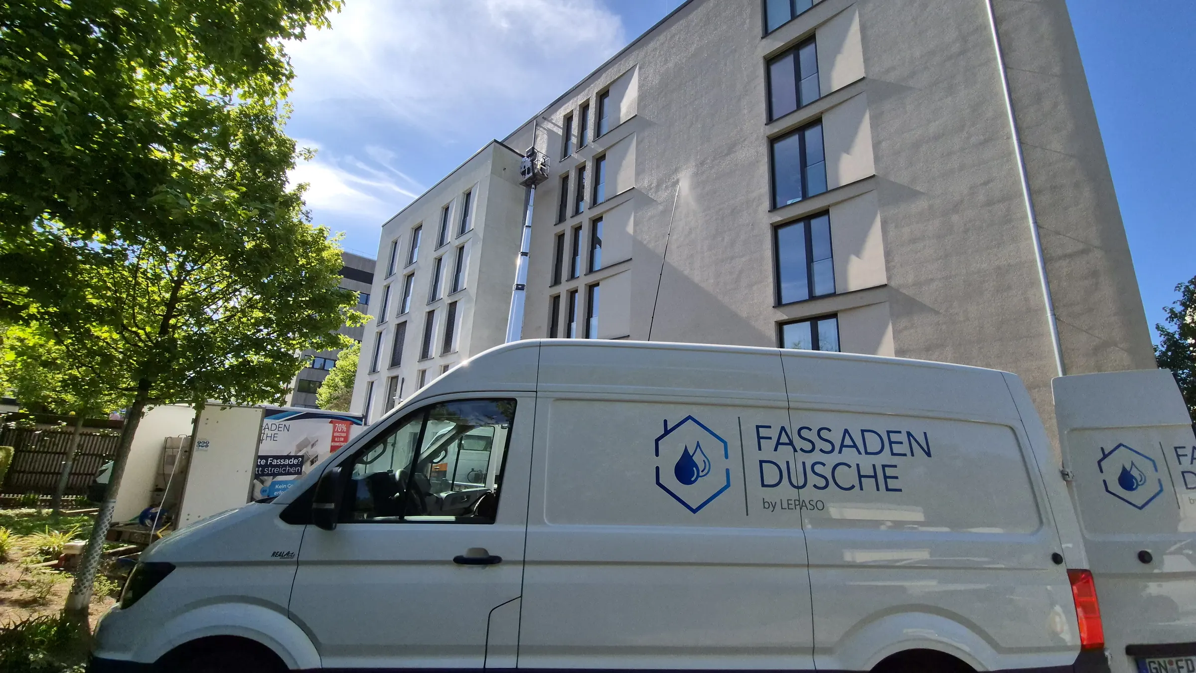 Fahrzeug der Fassaden-Dusche vor einer Wohnanlage, im Hintergrund die Hebebühne