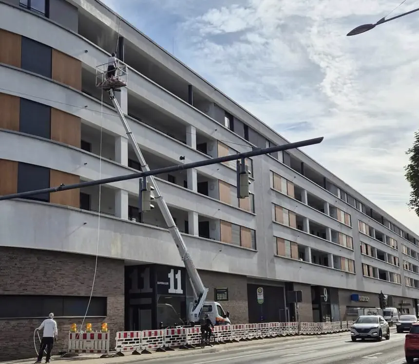 Hebebühne vor einem Wohn- und Geschäftskomplex in Offenbach während der Fassadenreinigung