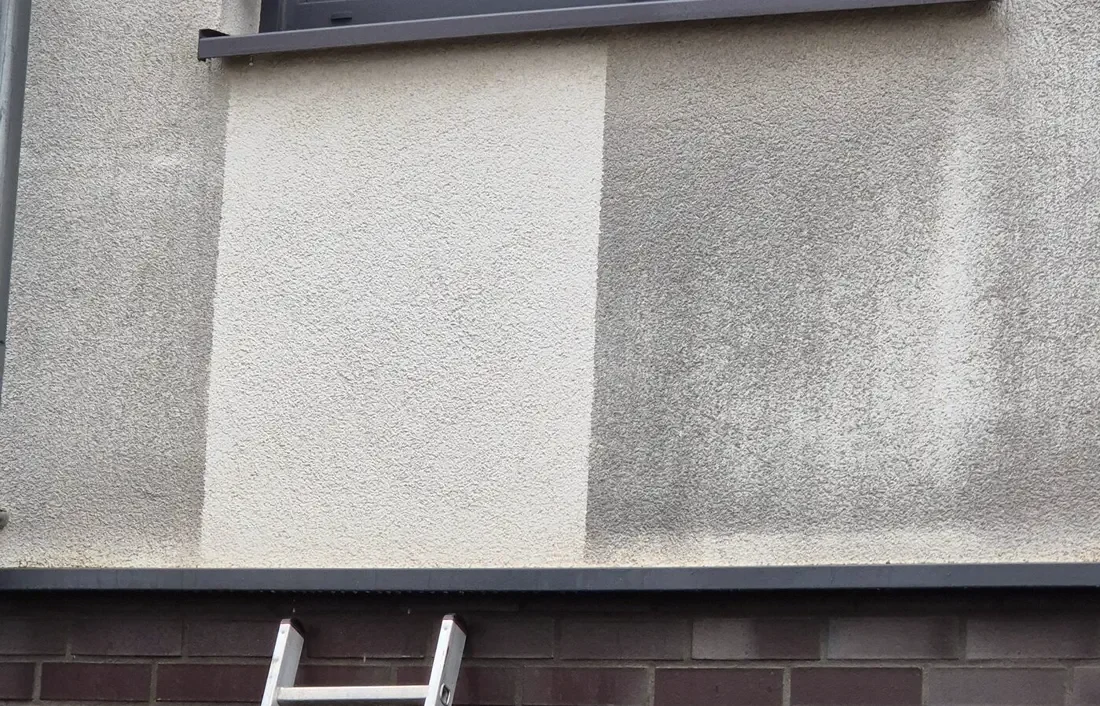 Probefläche an der Fassade: der gereinigte Bereich hebt sich hell vom Rest der Wand ab