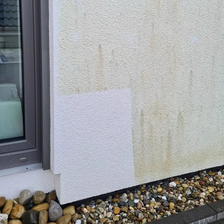 Probefläche an einer verfärbten Fassade: das gereinigte Feld ist wieder hell